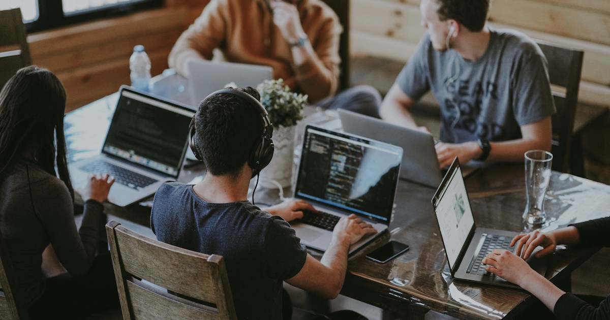 A team working together around laptops at a shared table