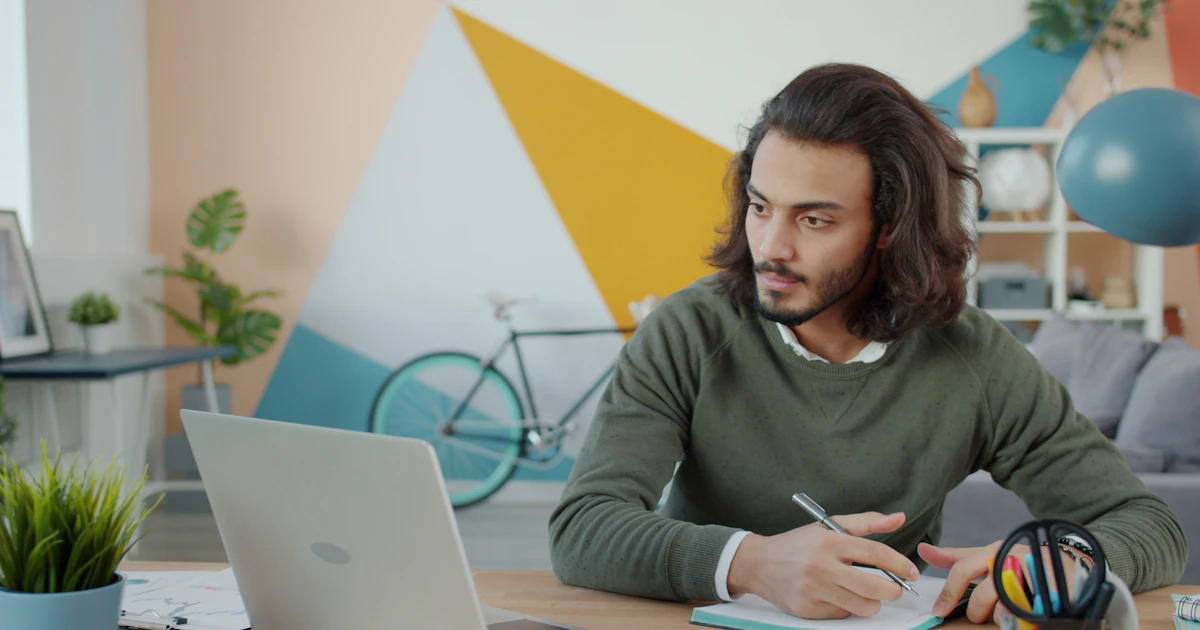 An independent professional taking notes beside a laptop.