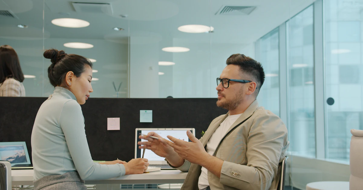 Two colleagues discussing work in a shared office.